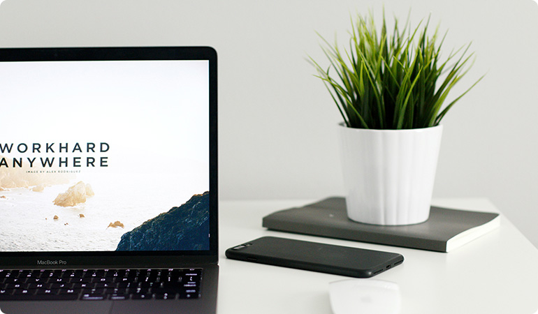 A laptop and phone sitting on top of a desk.